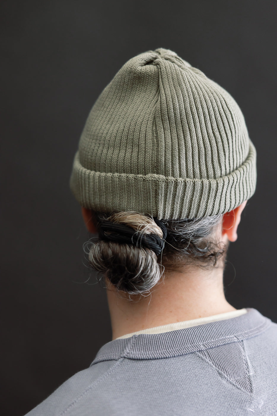 Close-up rear view of sage cotton roll-up beanie on male model, 5'9