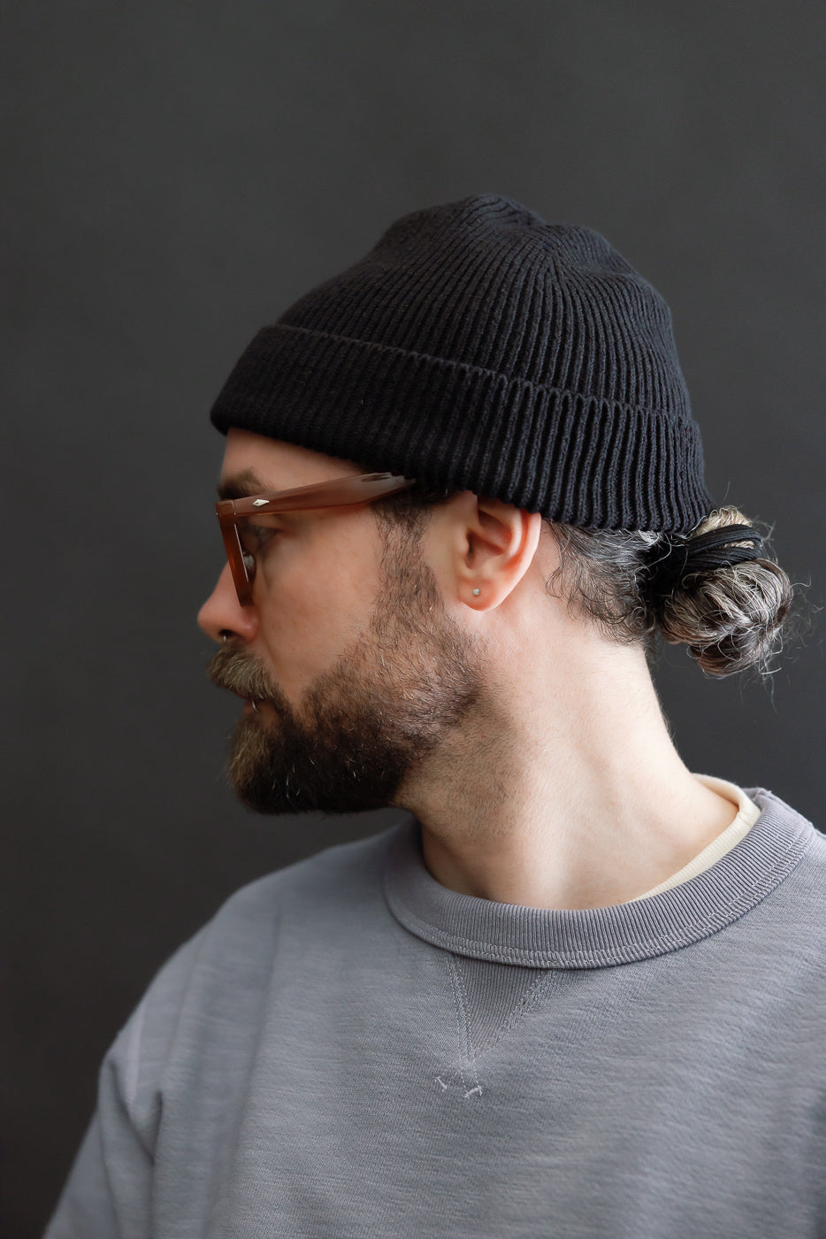 Male model 5'9 165lbs athletic build, close-up side view wearing black ribbed beanie, showing left side detail