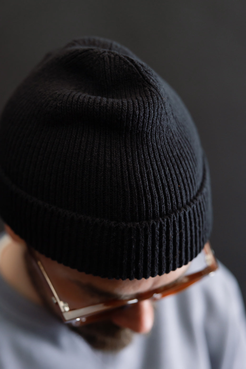 Close-up of black ribbed knit beanie on male model, 5'9