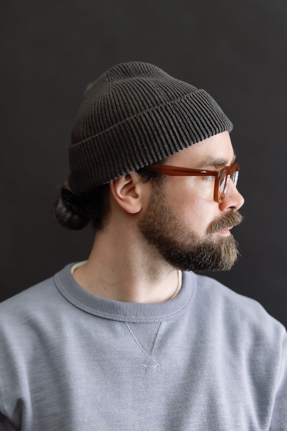 Close-up right side view of dark gray ribbed beanie on male model, 5'9