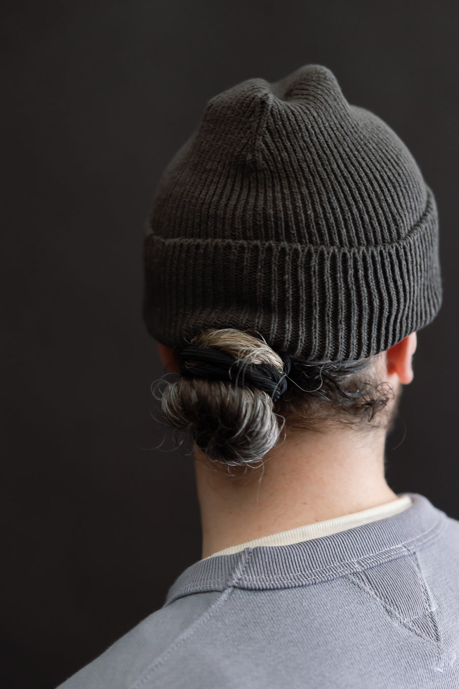 Close-up rear view of dark gray ribbed beanie on male model, 5'9