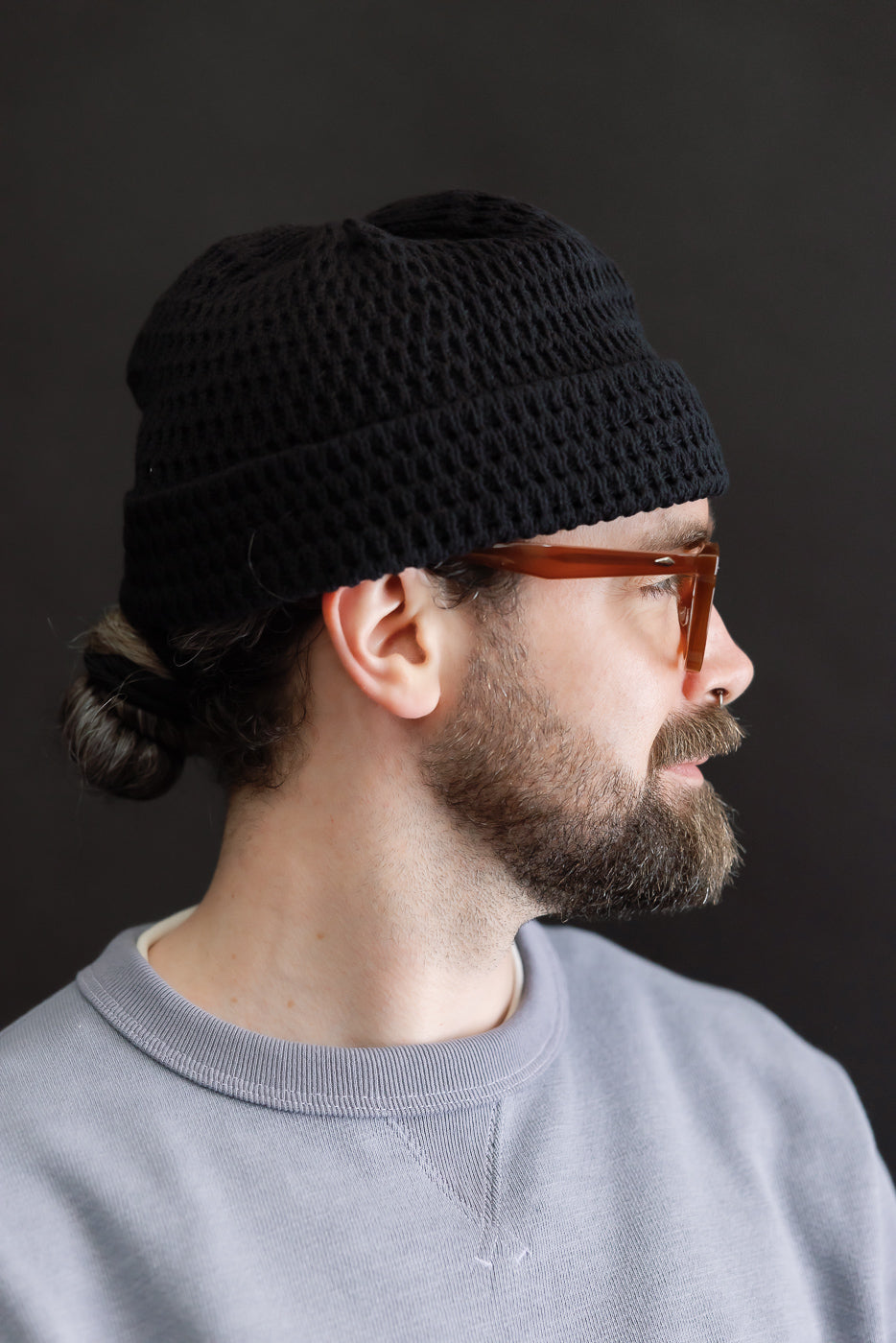 Side view close-up of recycled cotton open knit beanie in light black on male model, 5'9