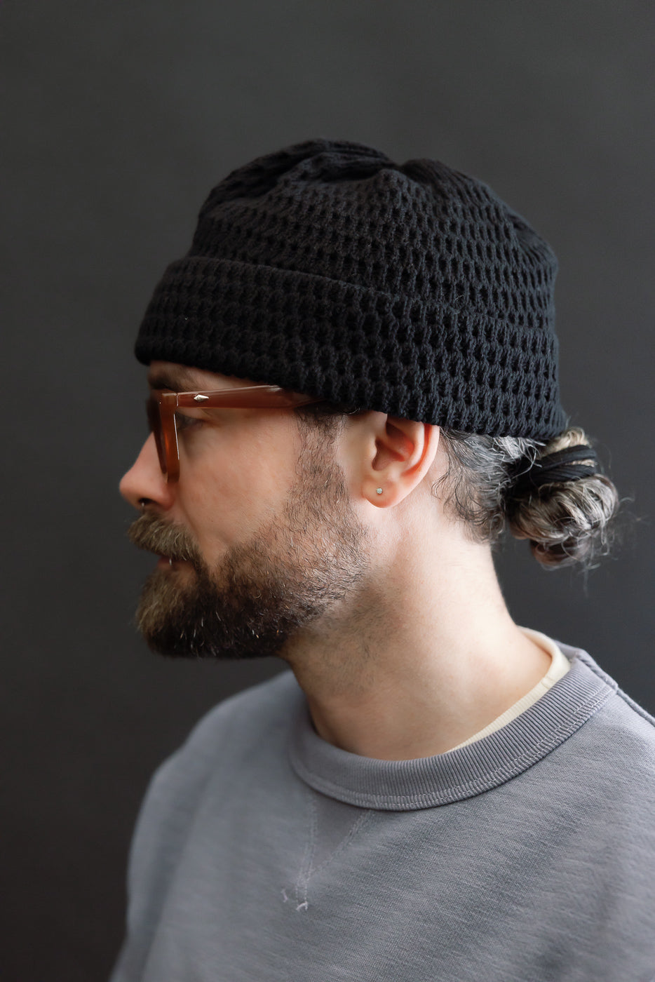 Side view close-up of recycled cotton open knit beanie in light black on male model, 5'9