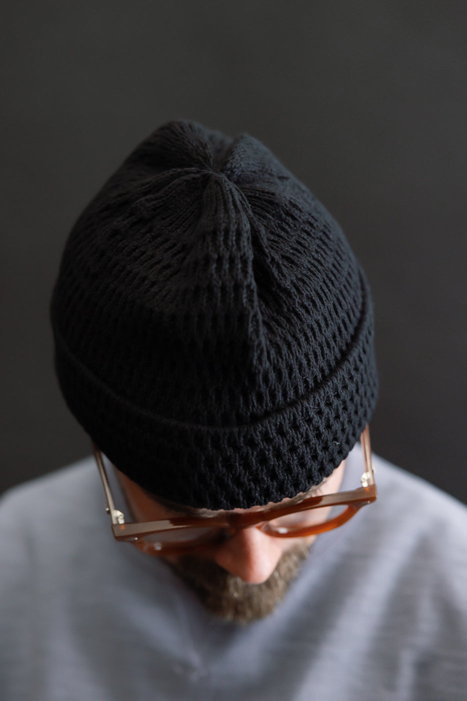 Close-up top view of open-knit recycled cotton beanie in light black on male model, 5'9