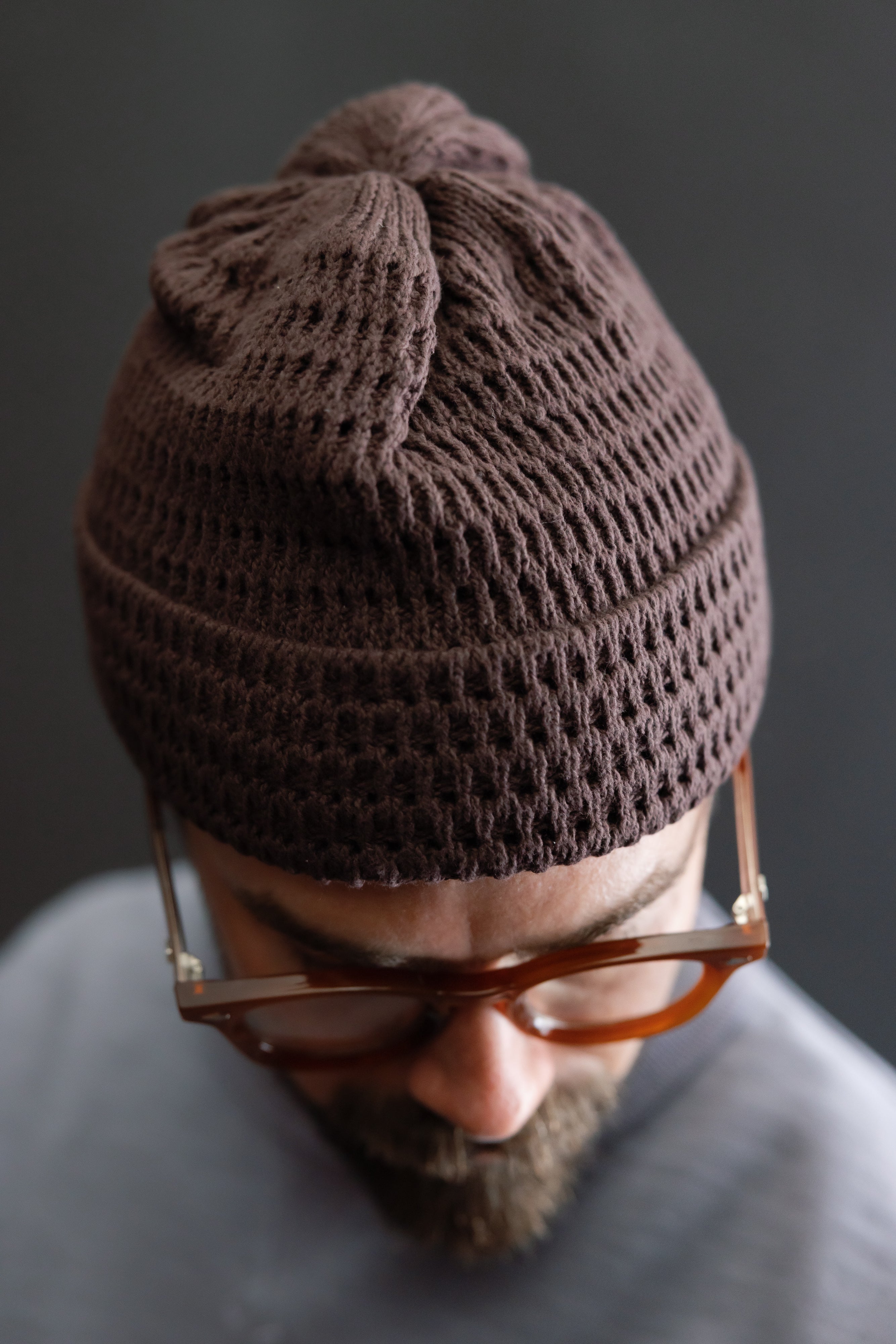 Close-up front view of light brown recycled cotton open knit beanie on male model, 5'9