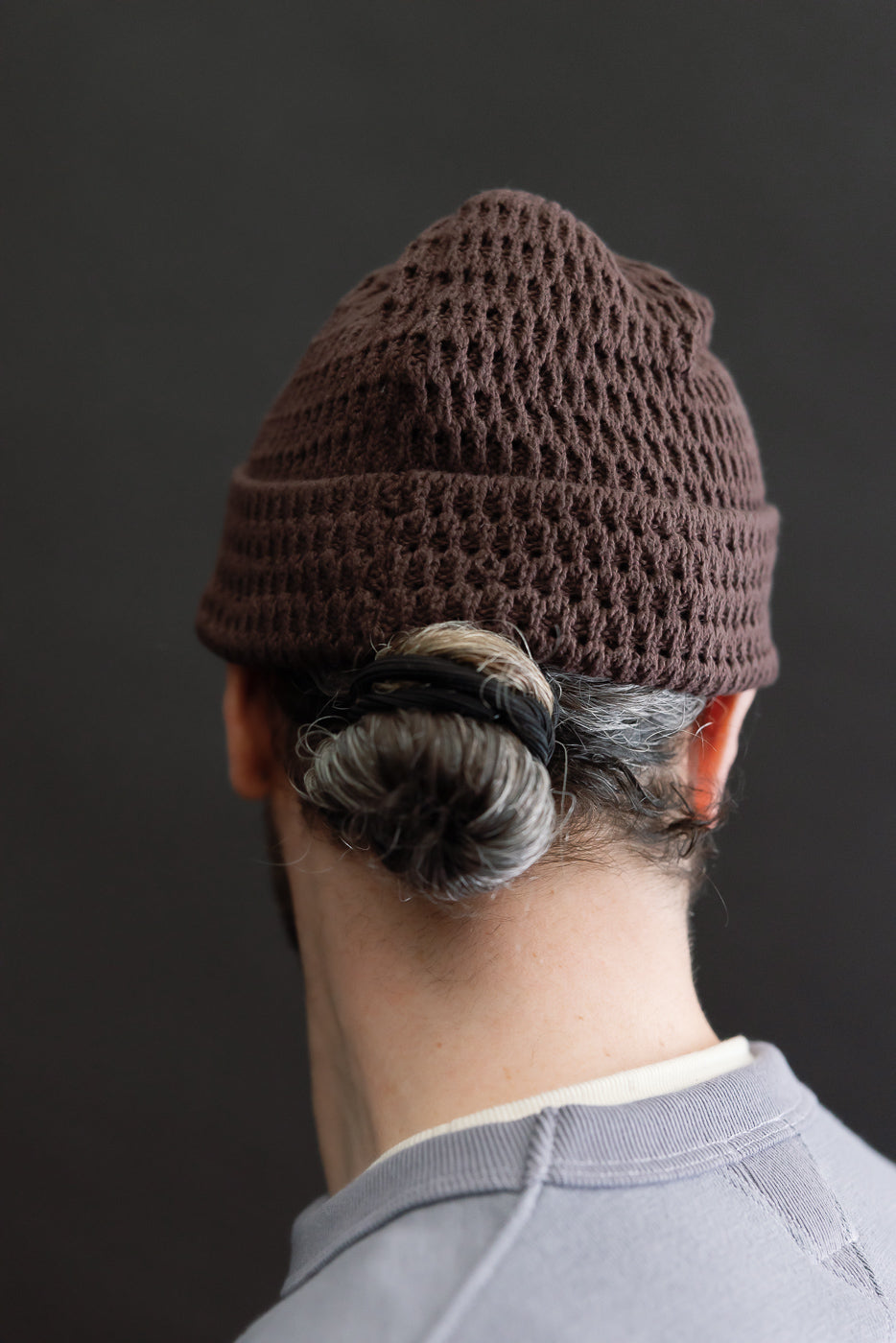 Rear close-up of recycled cotton open knit light brown beanie on male model, back view.