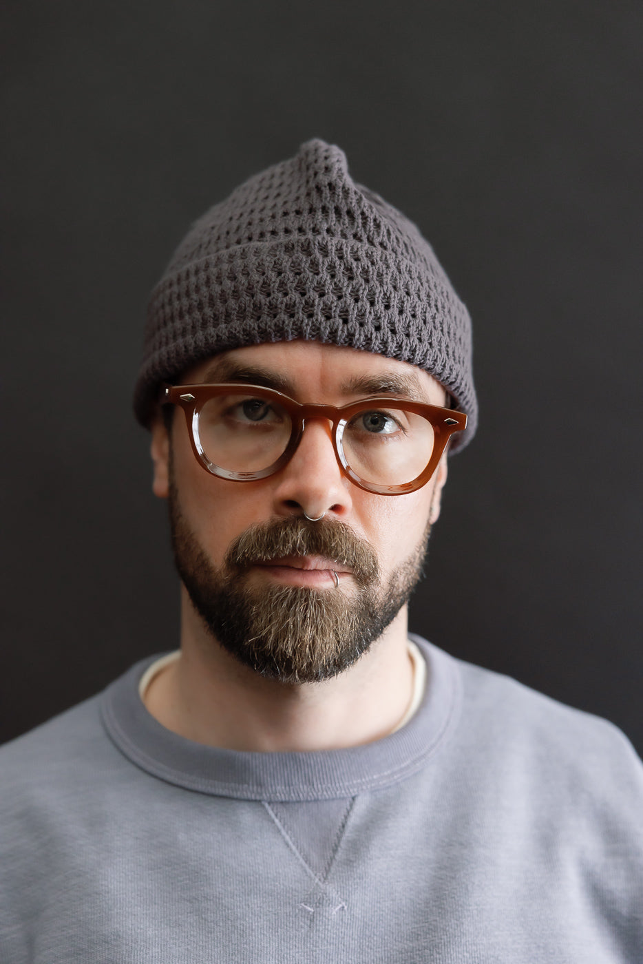 Front close-up of light charcoal recycled cotton open-knit beanie on male model, 5'9