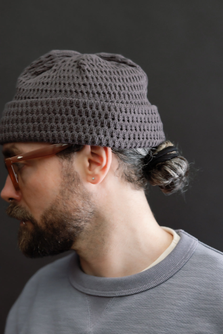 Close-up side view of recycled cotton open knit beanie in light charcoal on male model, 5'9
