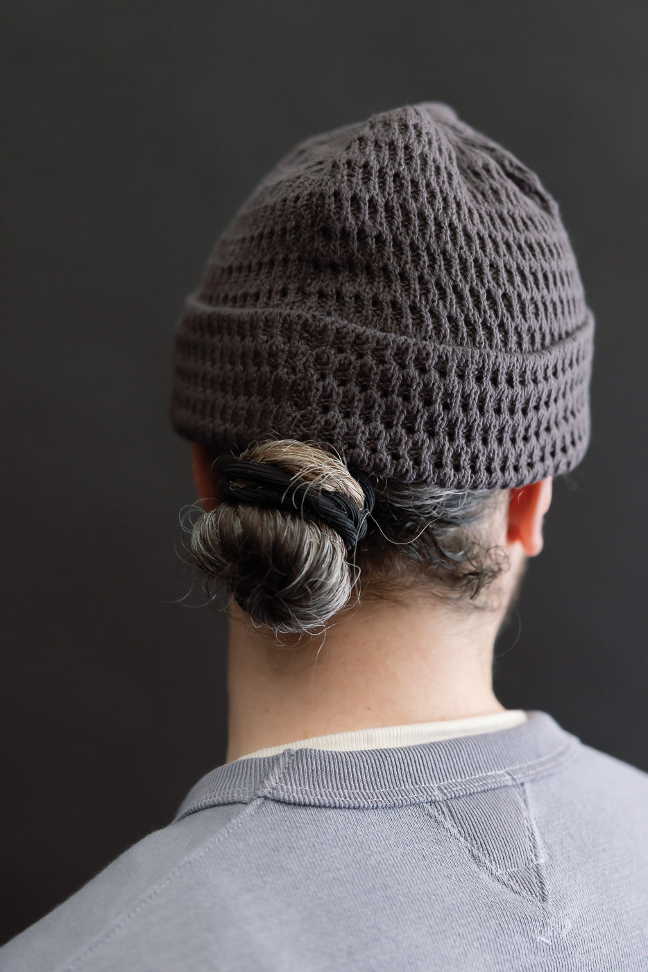 Back view close-up of recycled cotton open knit beanie in light charcoal on male model, 5'9