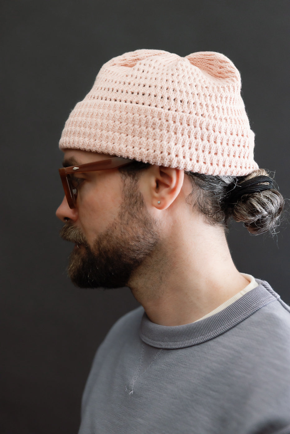 Side view close-up of light pink open-knit beanie on male model, 5'9
