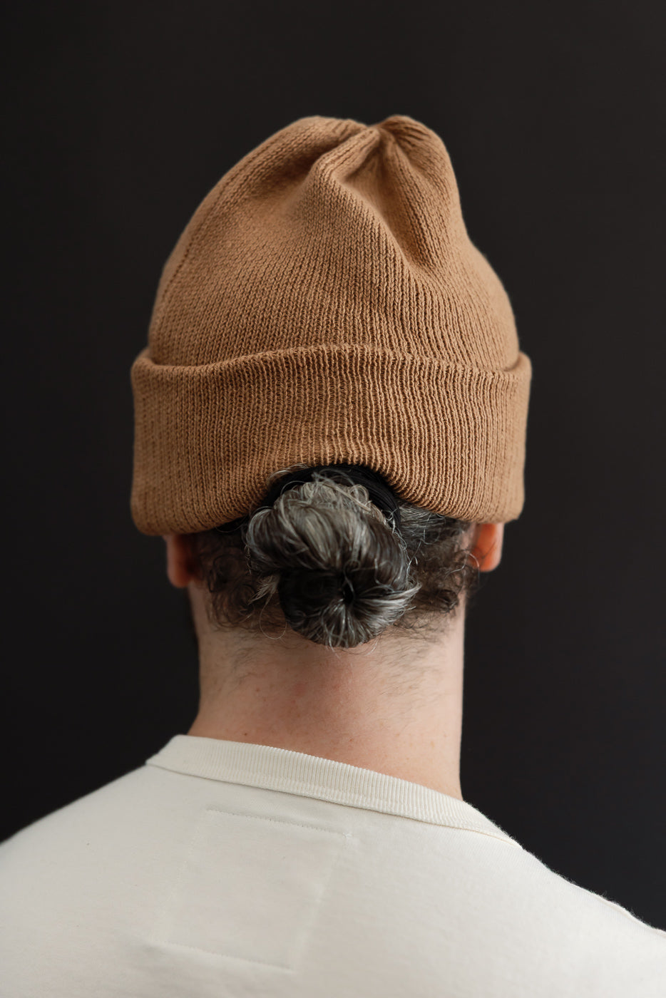 Back close-up of a tan ribbed beanie on a male model, 5'9