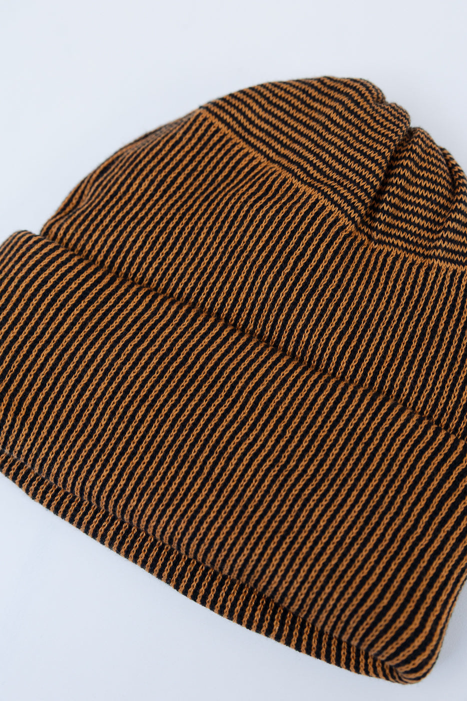 Front view flat lay of a brown and black striped knit beanie hat.