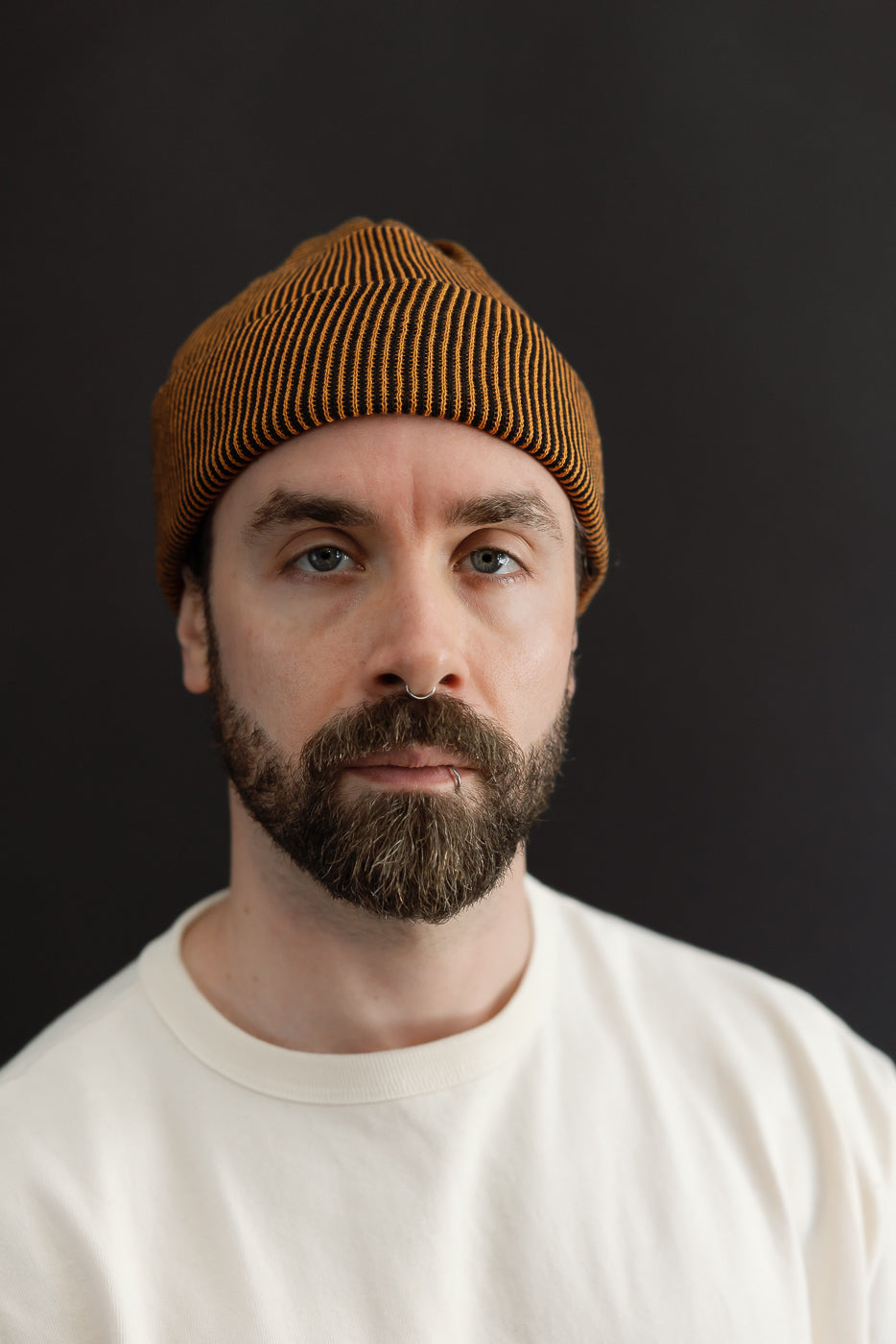 Close-up front view of a male model wearing a mustard yellow ribbed beanie.