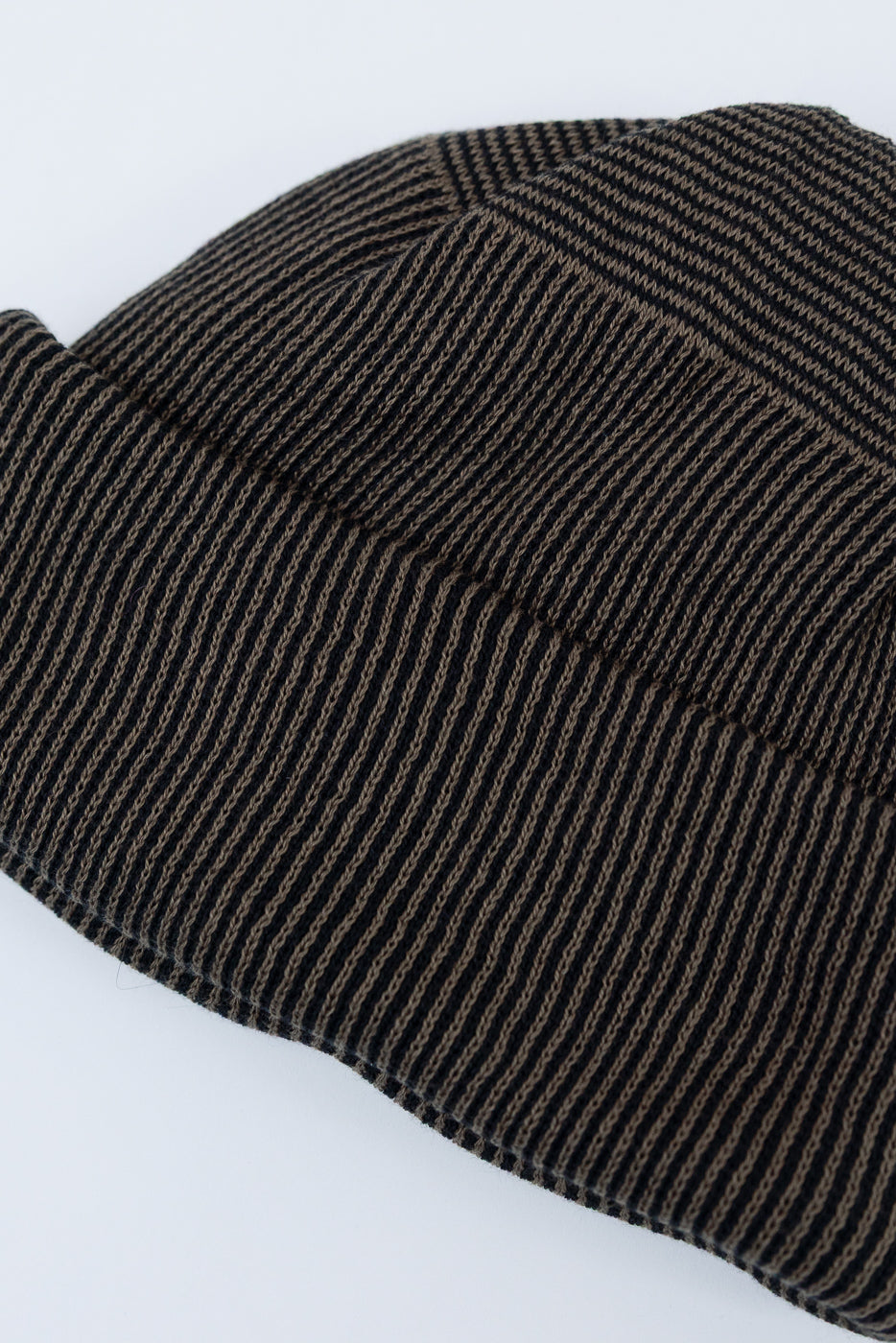 Close-up of the ribbed fabric texture on a brown and black striped beanie hat.