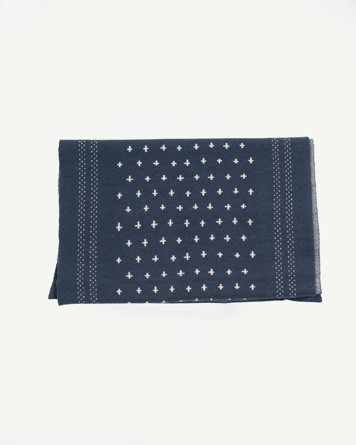 Flat lay of the front of a navy blue fabric accessory with white cross patterns.