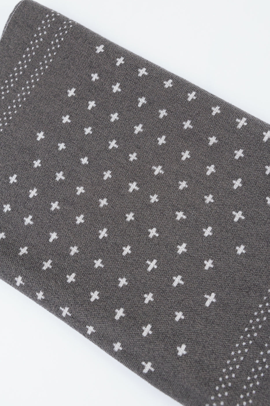 Close-up of grey knit fabric with white cross patterns, showing the textile texture.