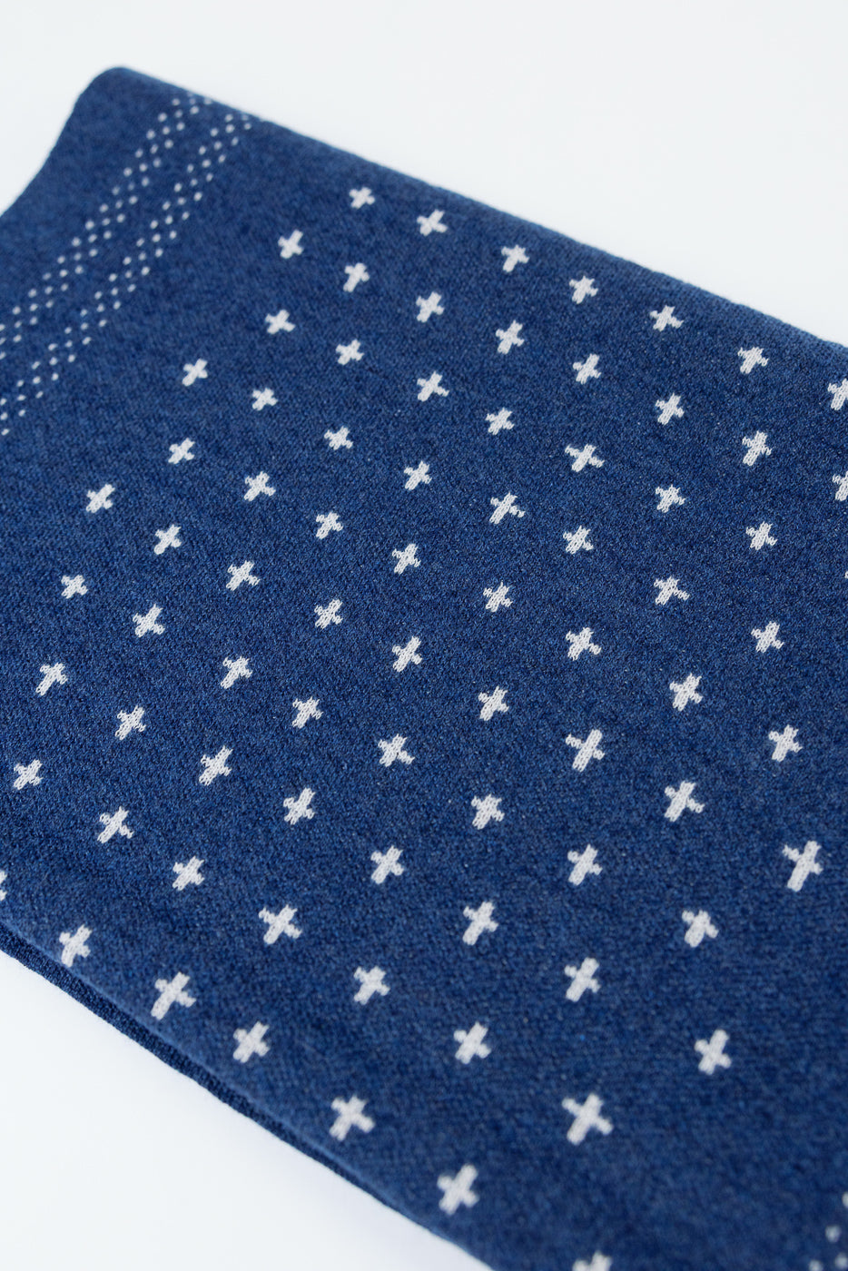 Close-up of the front texture and white cross pattern on blue knit fabric.
