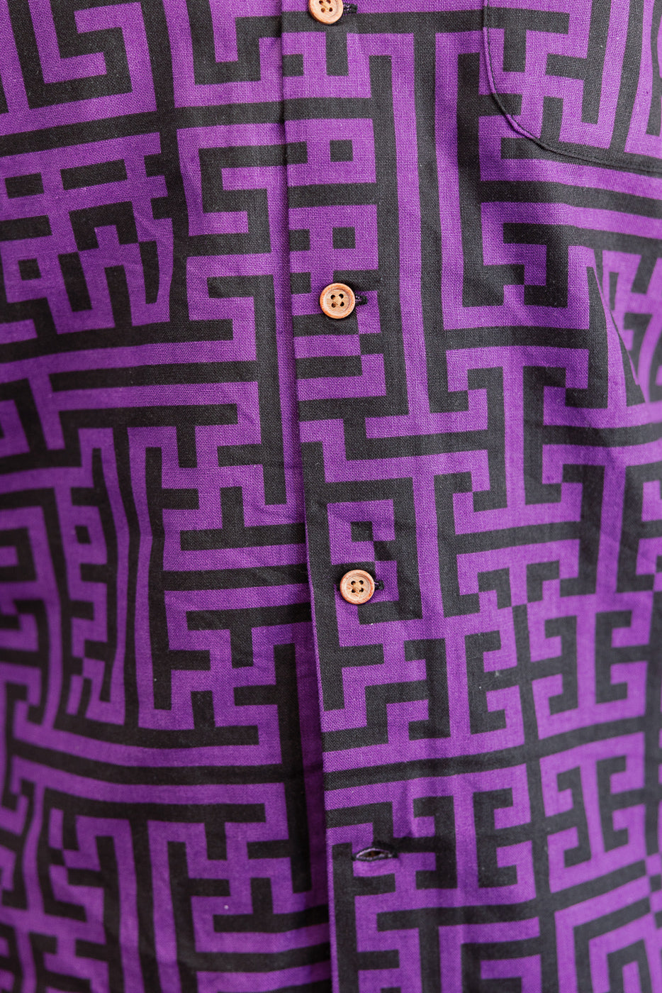 Close-up front view of purple shirt with black geometric maze print, wooden buttons, and chest pocket detail