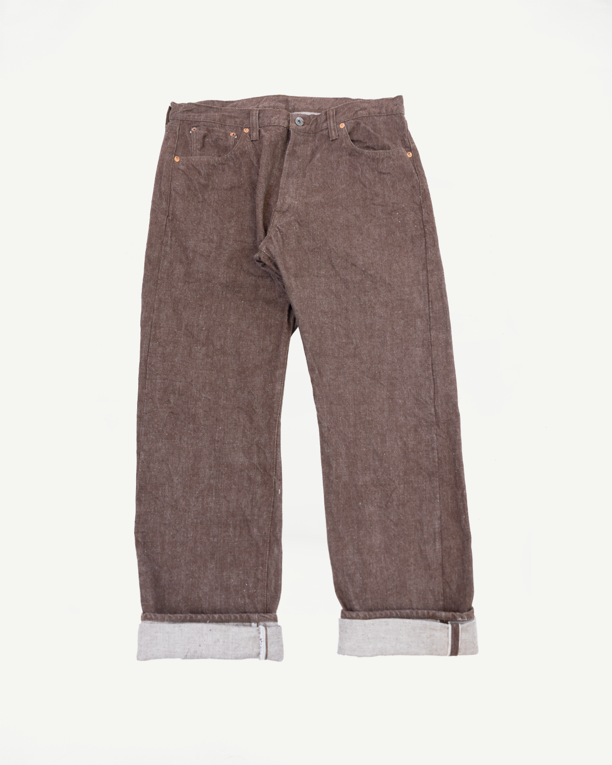 Flat lay front view of brown selvedge jeans with cuffed hems, copper rivets, and visible selvedge edge