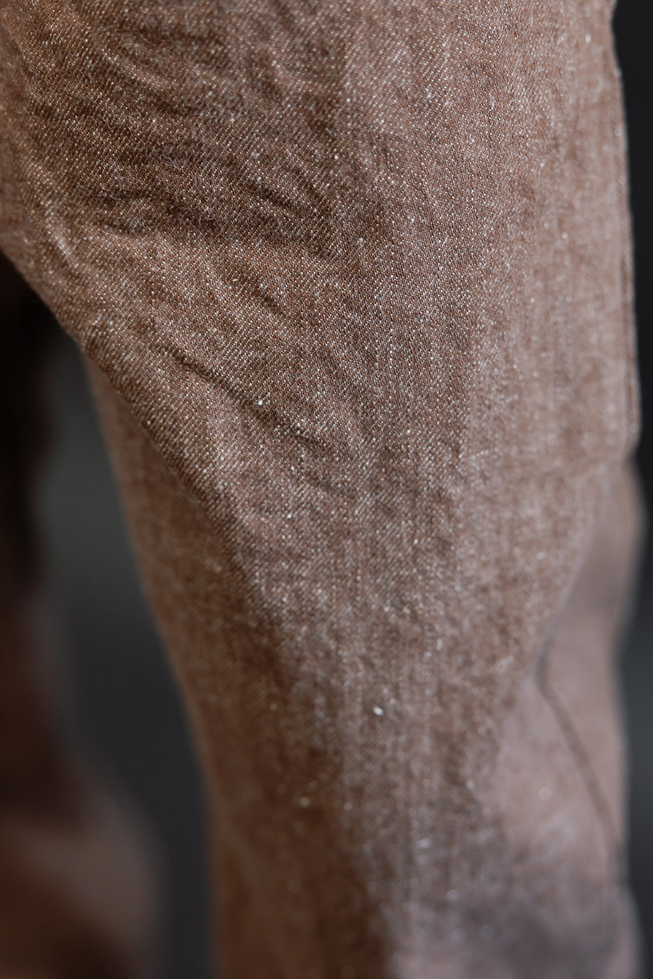 Close-up side view of brown selvedge denim pants showing fabric texture and weave detail on male model