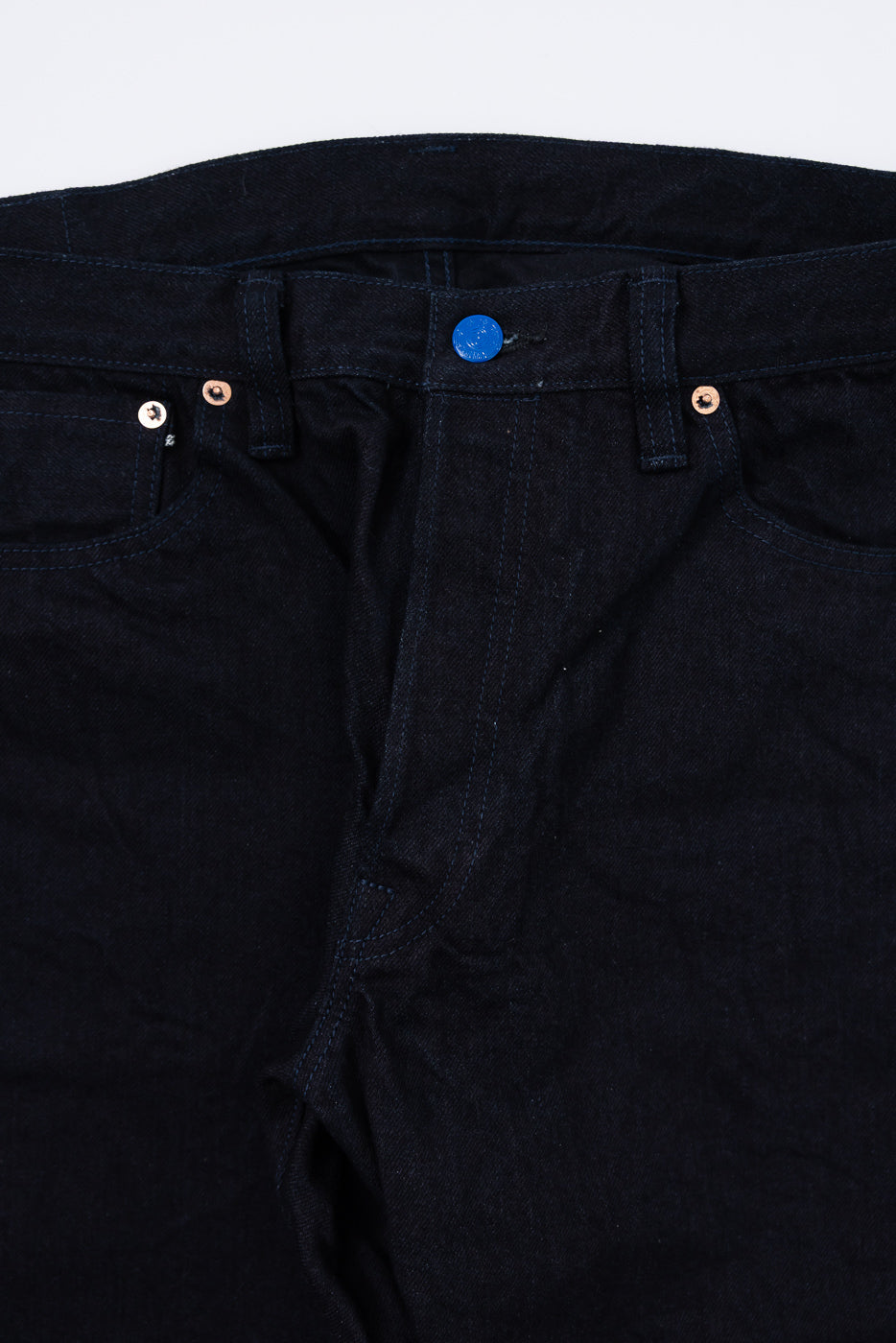 Close-up front detail of Samurai S0510XX BOB 15oz Aoki Tachikage black blue selvedge denim jeans, highlighting blue top button and copper rivets.