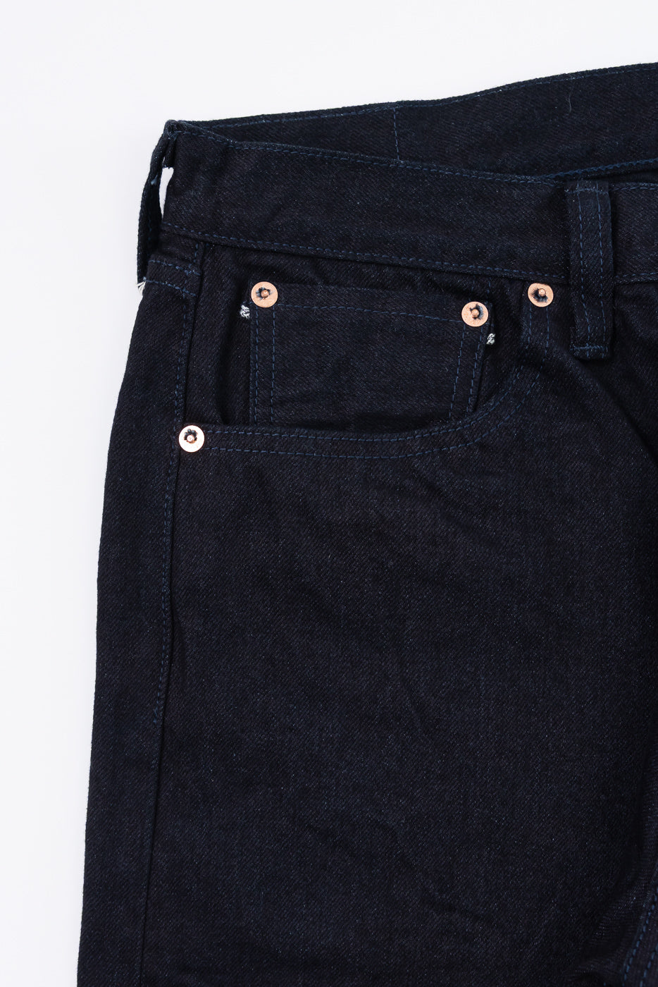 Close-up of front left pocket and rivets on black blue selvedge denim jeans