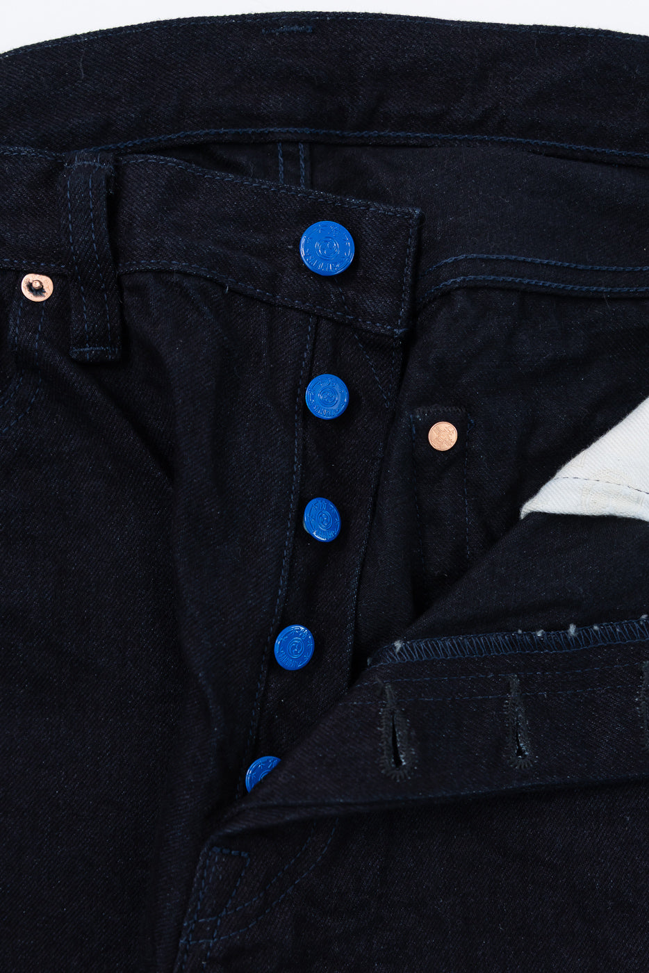 Close-up of Samurai S0510XX Aoki Tachikage black blue selvedge denim jeans front fly, showing blue buttons and indigo fabric texture from Dant Indianapolis.
