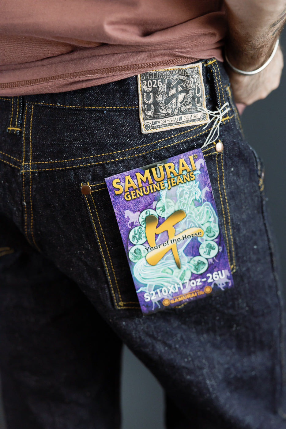Close-up of male model's back pocket showing Samurai Jeans tag, 17oz selvedge denim, yellow stitching