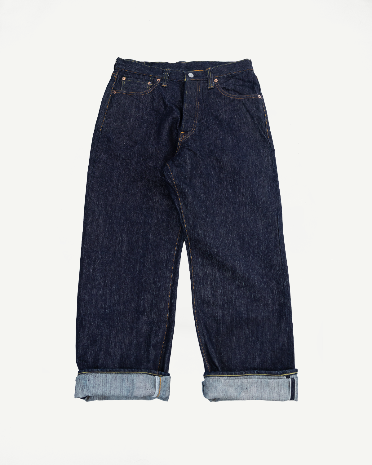 Front view of dark selvedge denim jeans, cuffed hem showing raw edge, classic 5-pocket design, flat lay