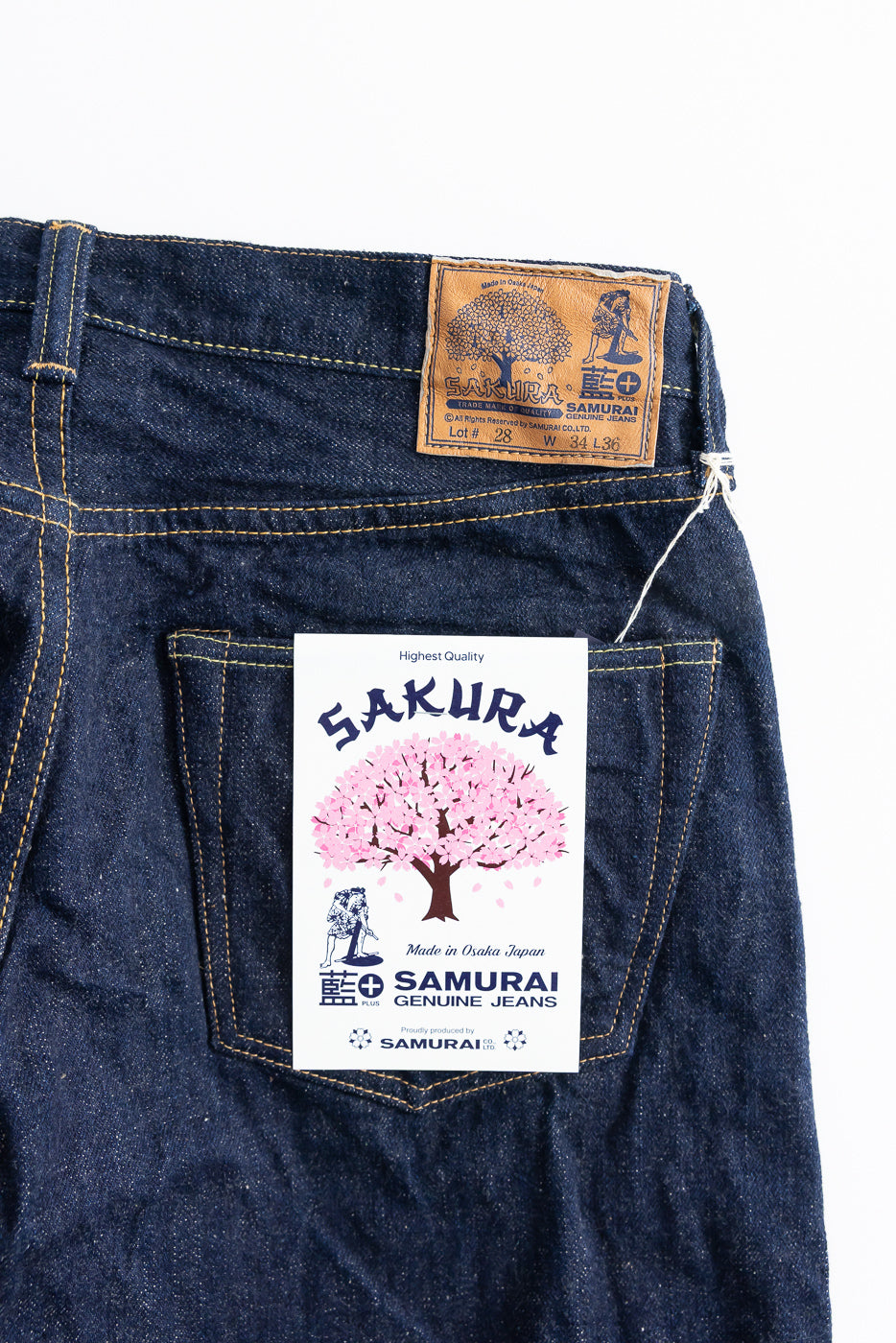 Close-up of the back upper section of selvedge jeans showing leather patch, rear pocket, and Sakura tag