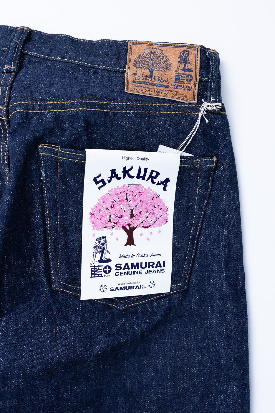 Close-up of Samurai's S500AX-SAKURA jeans' back pocket, featuring a Sakura graphic hang-tag and embossed leather patch, showcasing the intricate craftsmanship of this limited-edition denim.
