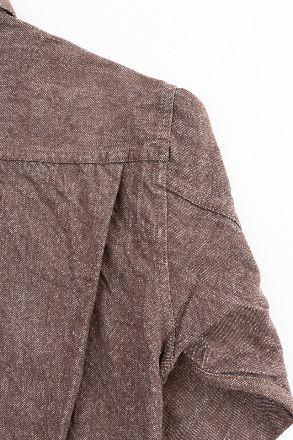 Close-up front shoulder & sleeve of brown textured shirt, showing fabric weave and stitching detail