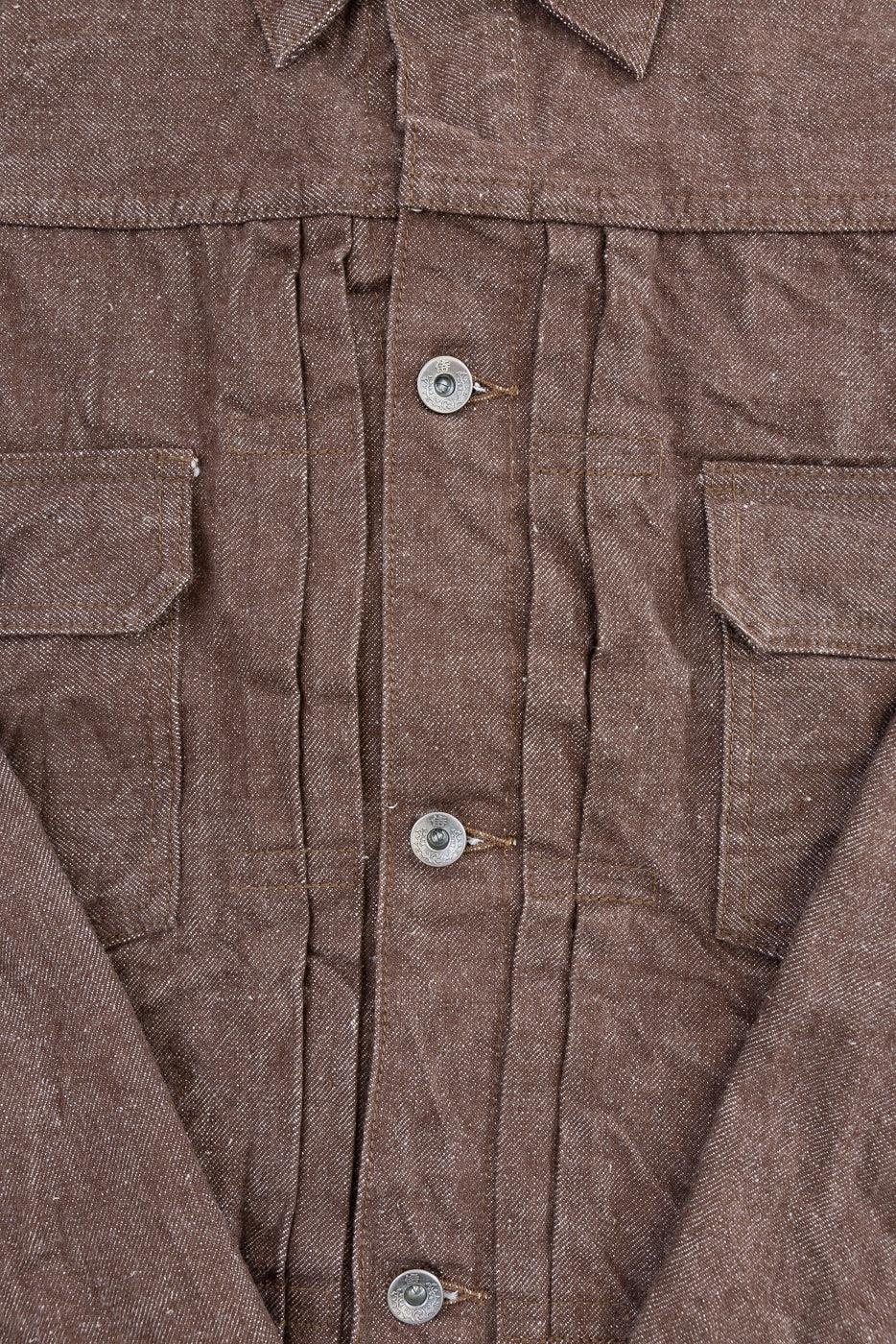 Close-up front view of brown selvedge work shirt, showing button placket, chest pockets, and textured fabric weave