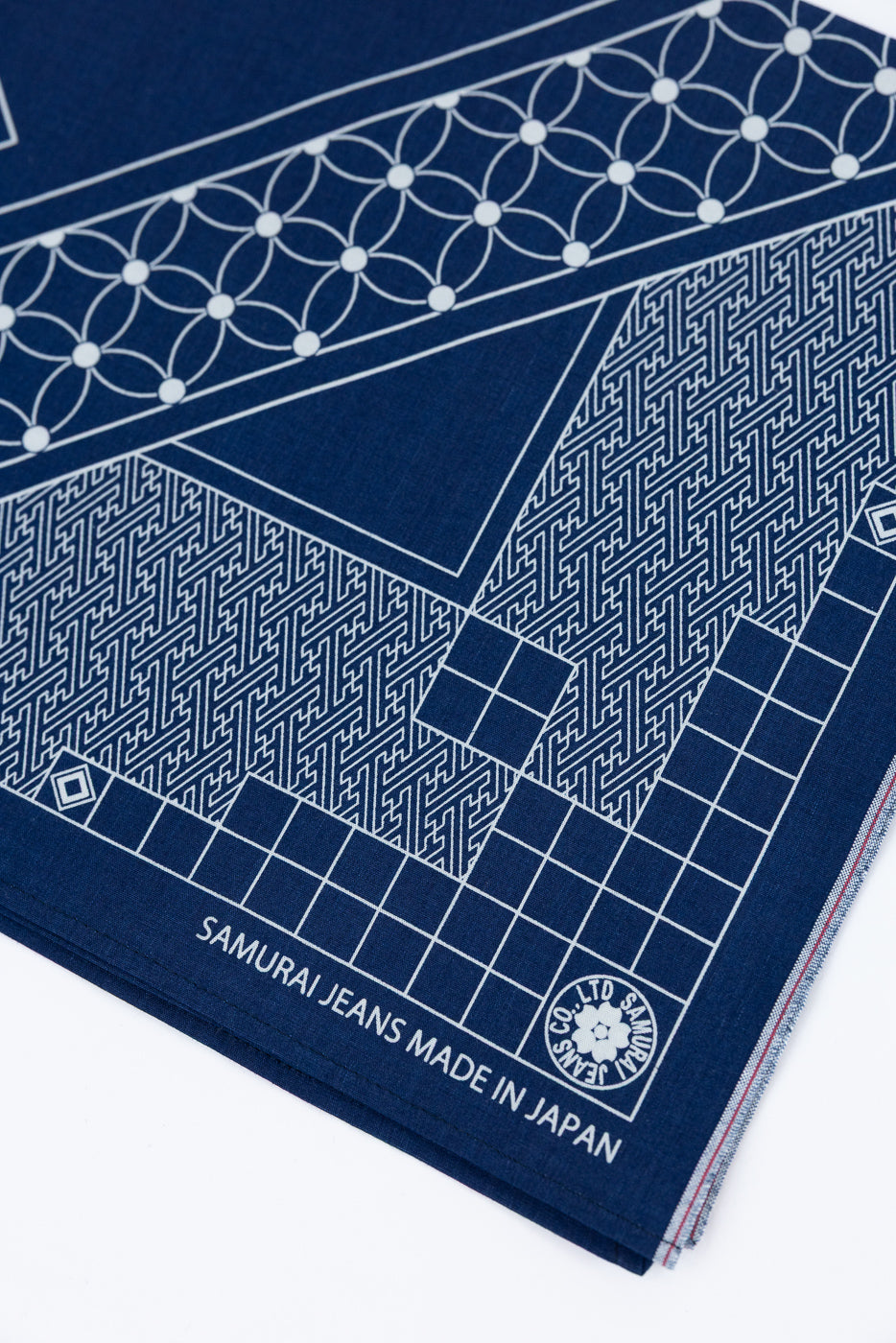 Close-up of navy bandana front, showing geometric white patterns, 'SAMURAI JEANS MADE IN JAPAN' text, and logo detail.