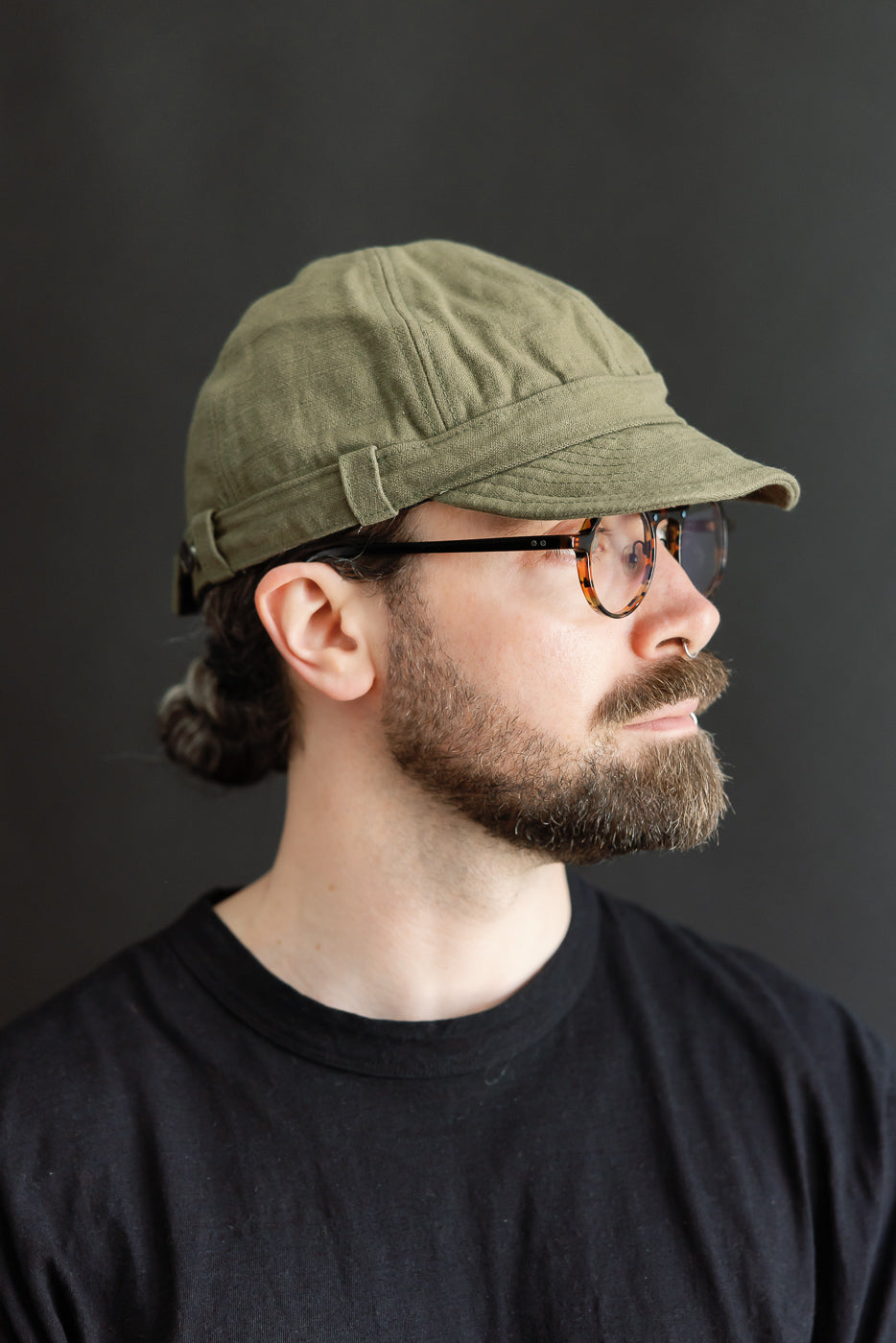 Male model 5'9, 165lbs, athletic build wearing olive heavy back satin work cap, right side close-up