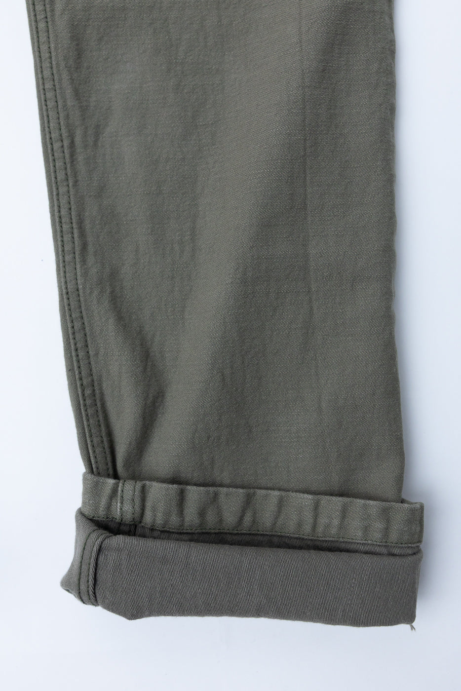 Close-up of olive green pants hem, showing rolled cuff and fabric texture