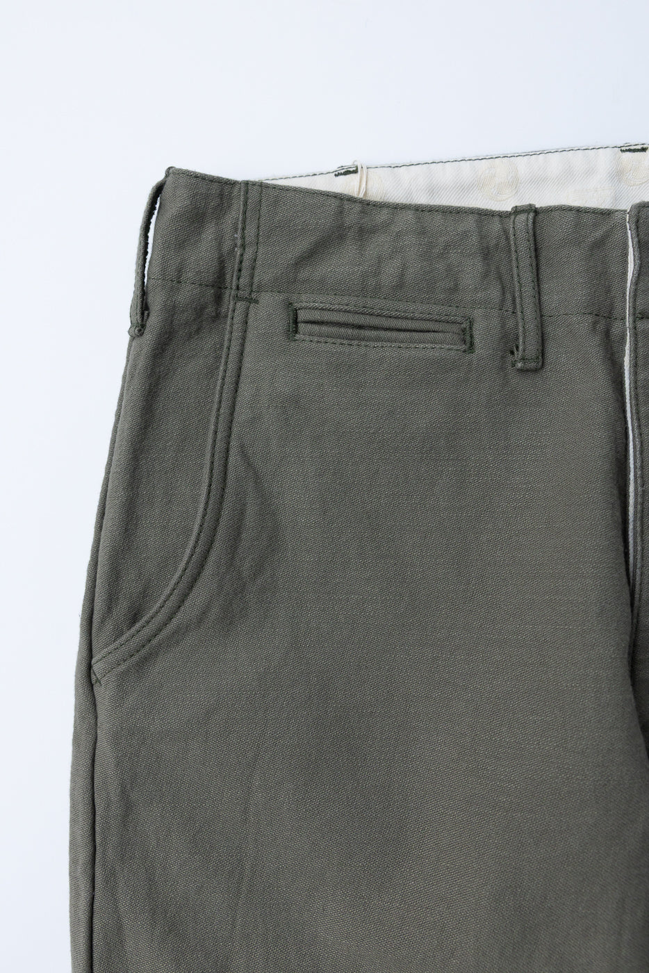 Close-up front view of olive green casual pants showing waistband, belt loops, and front pocket detail.