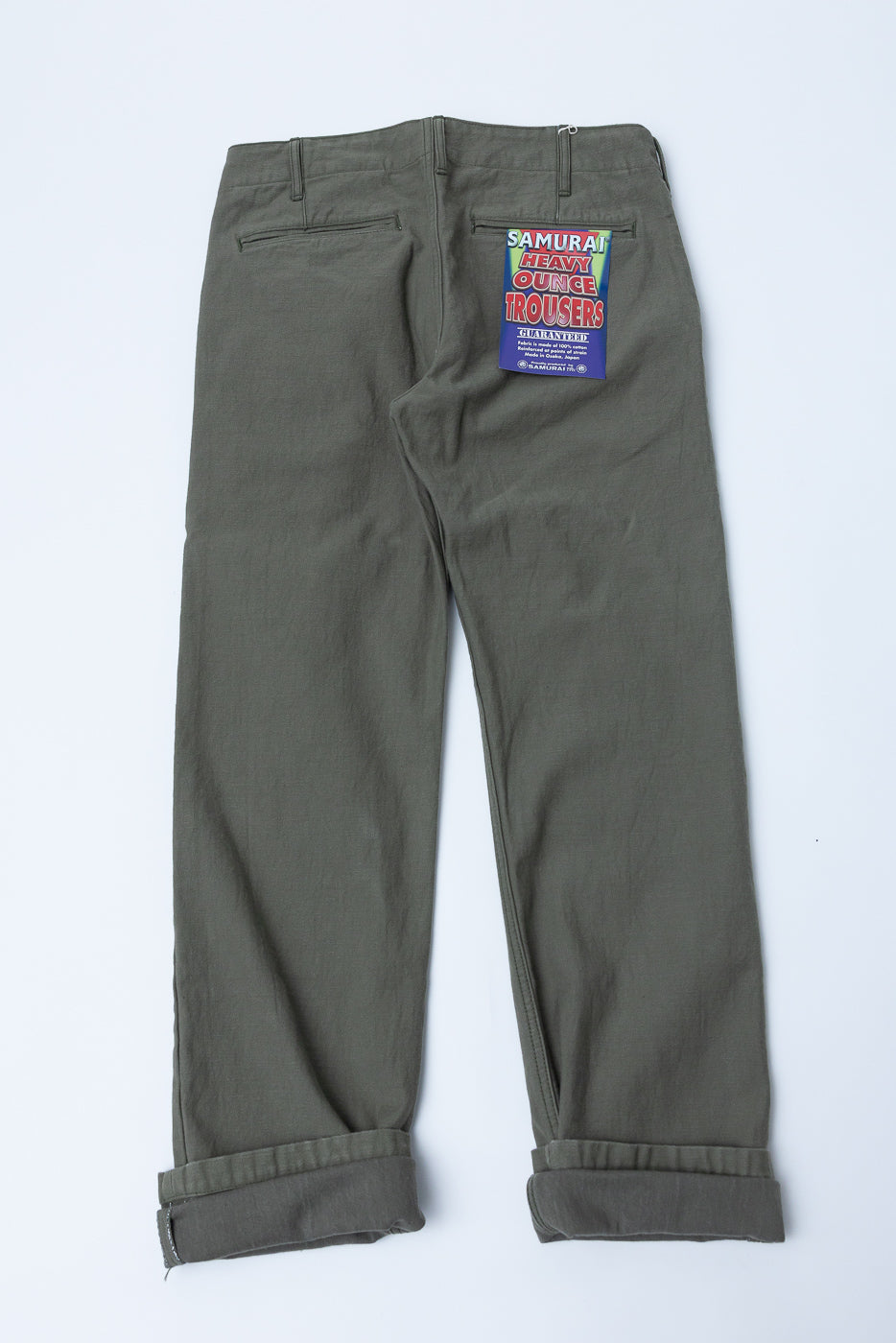 Back view flat lay of olive green Samurai Heavy Ounce Trousers with cuffed hems and brand tag visible