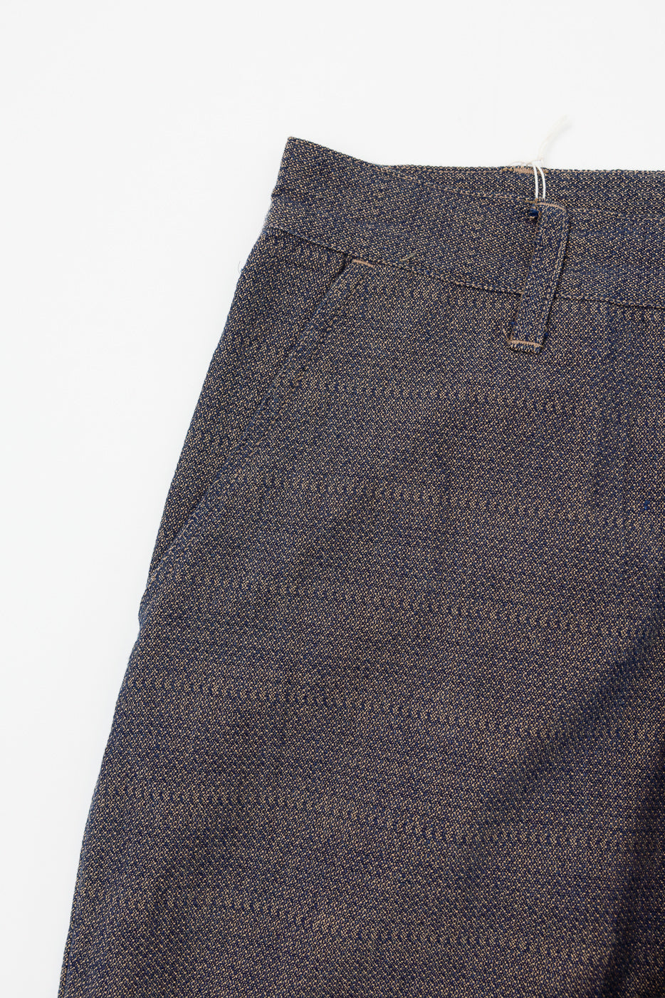 Close-up front view of textured selvedge trousers, showing waistband, belt loop, and fabric weave detail