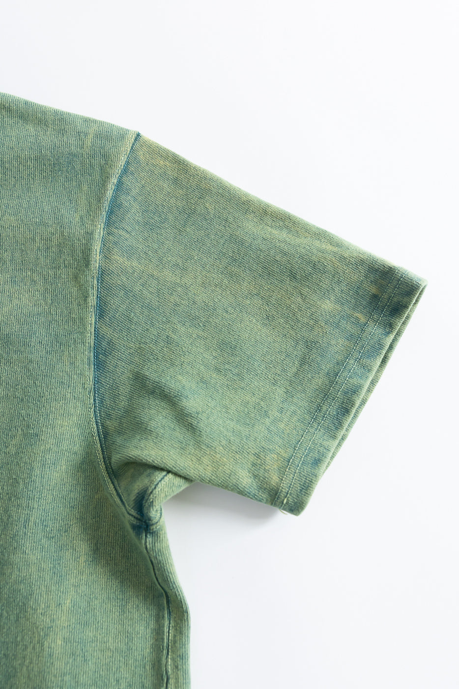 Close-up of green extra heavy t-shirt, flat lay, front right sleeve and shoulder fabric texture.