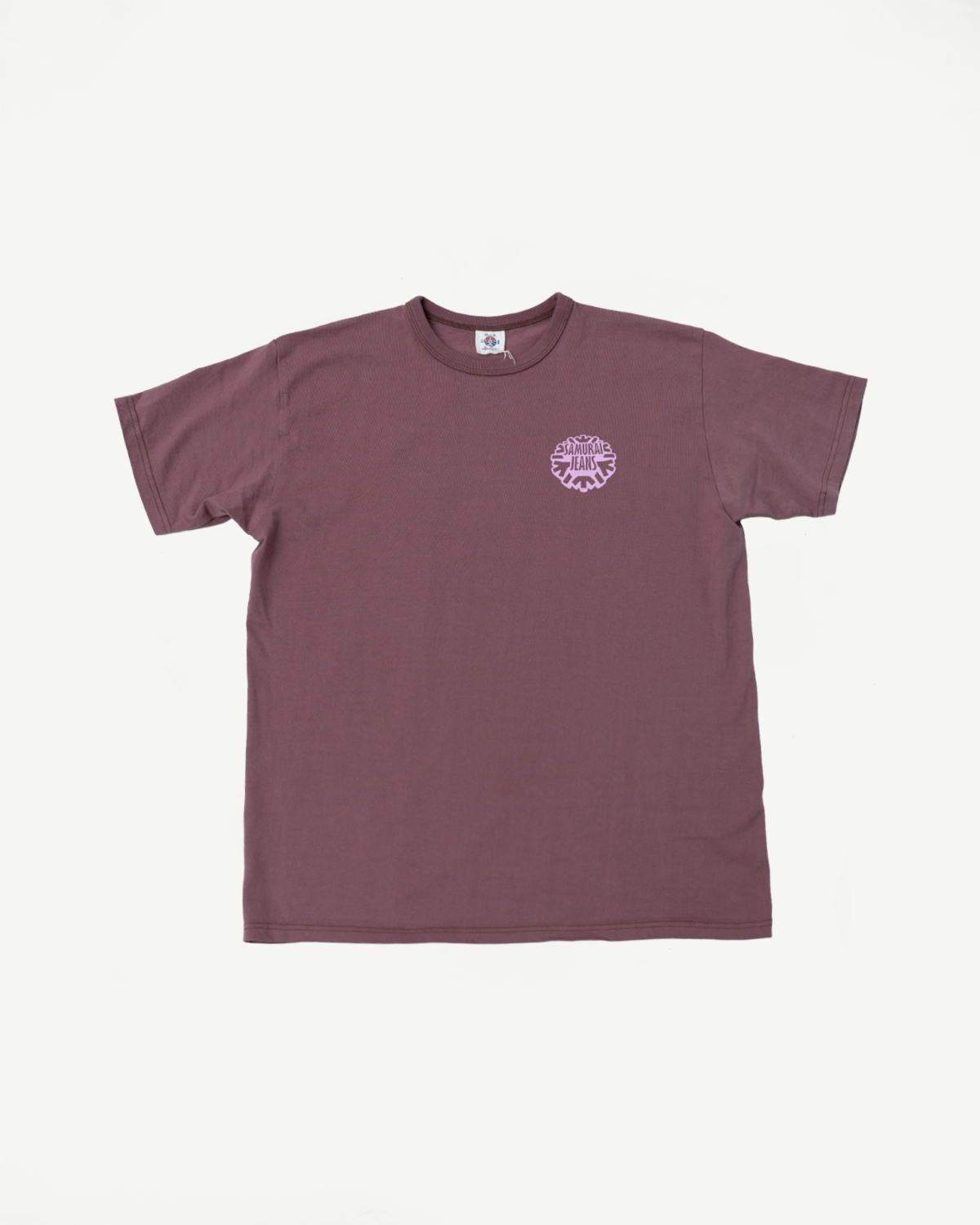 Flat lay front view of mauve short-sleeve tee with purple Samurai Jeans logo, ribbed crew neck, and tag detail