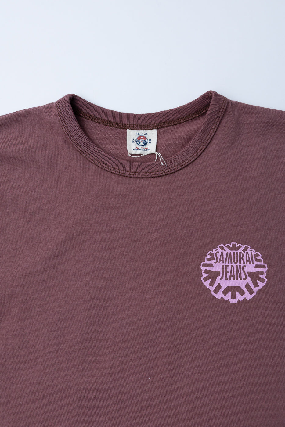 Close-up front view of maroon tee with Samurai Jeans logo, ribbed crew neck, and brand tag visible