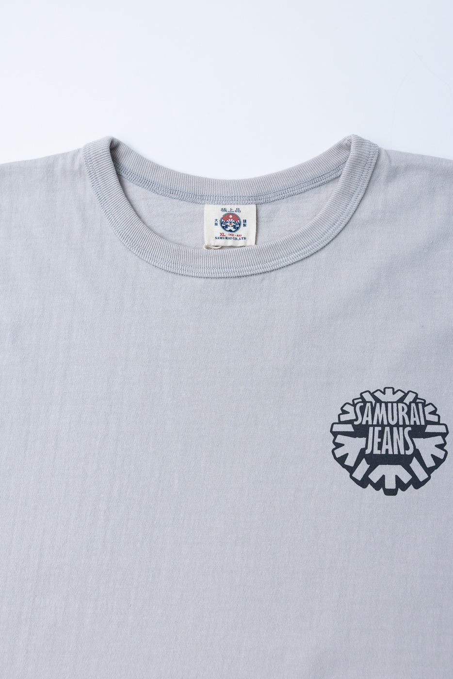Close-up front of gray t-shirt with Samurai Jeans logo, tag details visible