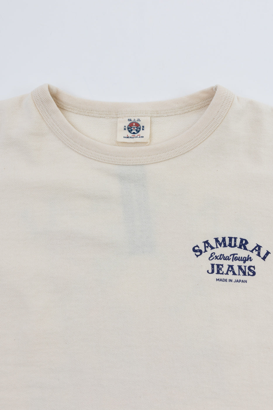 Close-up front view of cream Samurai Extra Tough Jeans tee, showing collar tag and chest logo, made in Japan