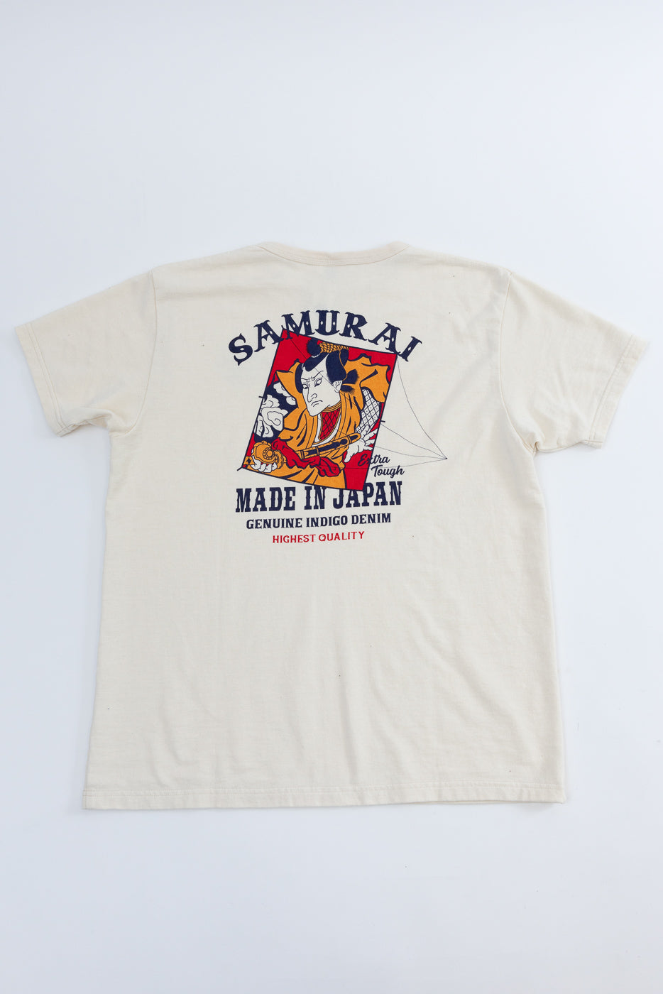 Back view of cream t-shirt with Samurai graphic, 'Made in Japan' text, and indigo denim quality print on flat lay.