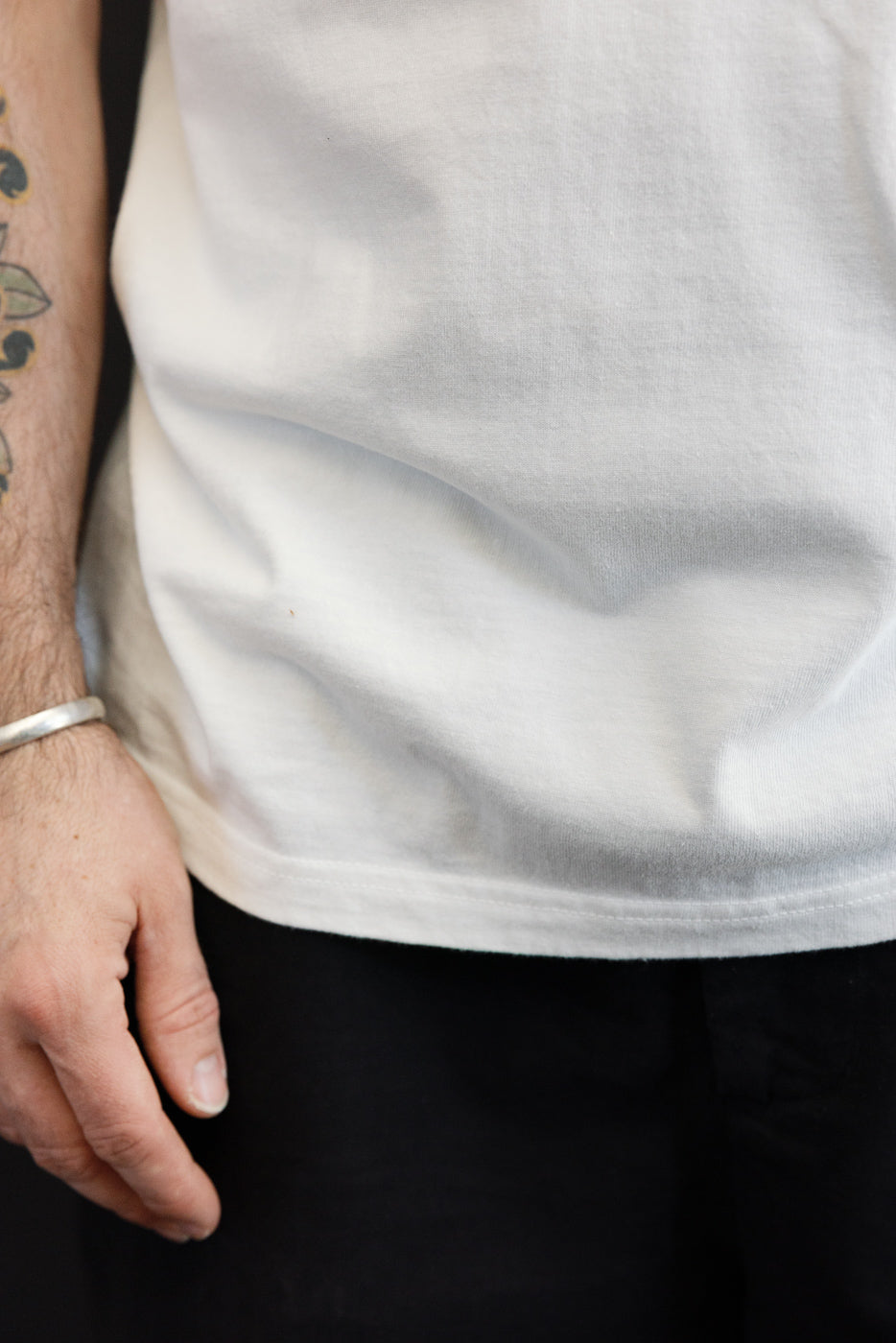 Close-up front view of white tee hem on male model, 5'9