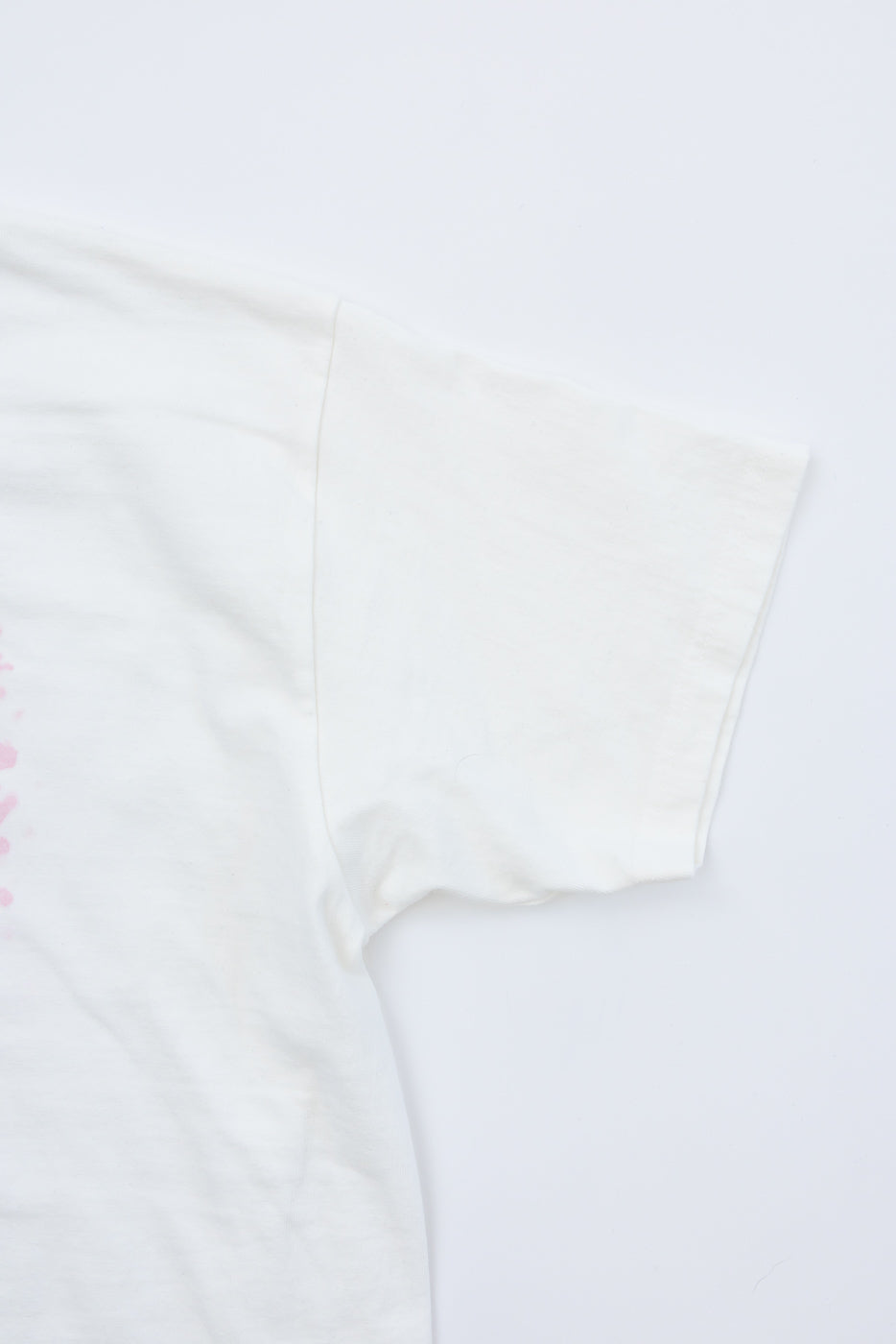Close-up front view of white tee sleeve, showing soft cotton texture and clean hem detail