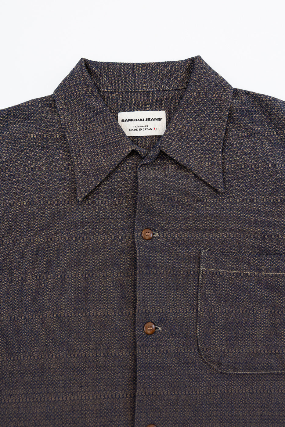 Close-up front view of dark selvedge work shirt with Samurai Jeans tag, button placket, chest pocket, and textured weave
