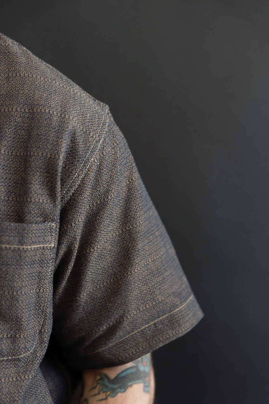 Close-up of male model's shoulder, showing textured fabric and sleeve detail on casual shirt