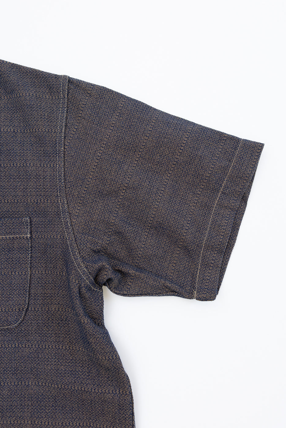 Close-up front view of dark selvedge denim shirt sleeve, showing texture and stitching detail